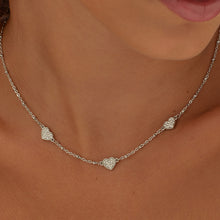 Carica l'immagine nel visualizzatore di Gallery, Collana con tre cuori e pietre applicate su di essi in acciaio color argento di sagapo indossata e vista da vicino