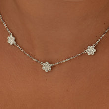 Carica l'immagine nel visualizzatore di Gallery, Collana con tre fiori e pietre applicate su di essi in acciaio color argento di sagapo indossata e vista da vicino