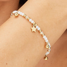 Carica l'immagine nel visualizzatore di Gallery, bracciale con charm a forma di stella sfere di vetro bianche e di acciaio dorato di sagapo glint indossato e visto da vicino