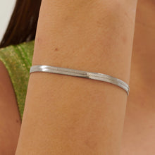 Carica l'immagine nel visualizzatore di Gallery, Bracciale con catena piatta a spina di pesce in acciaio lucido color argento, indossato e visto da vicino
