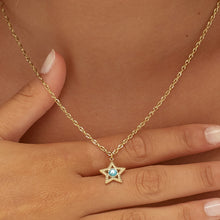 Carica l'immagine nel visualizzatore di Gallery, Collana con pendente a forma di stella in Acciaio dorato con cristallo azzurro al centro. indossata e vista da vicino