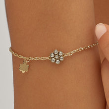 Carica l'immagine nel visualizzatore di Gallery, Bracciale con simbolo fiore in acciaio dorato lucido e cristalli bianchi di sagapo gioielli indossato da una ragazza e visto da vicino
