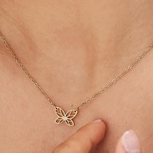 Carica l'immagine nel visualizzatore di Gallery, Collana con farfalla traforata e pietra bianca in metallo dorato indossata e vista da vicino
