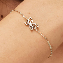 Carica l'immagine nel visualizzatore di Gallery, bracciale con farfalla traforata e pietra bianca in metallo dorato indossato e visto da vicino
