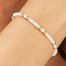 Carica l'immagine nel visualizzatore di Gallery, Bracciale con sfere in acciaio dorato sfere di vetro bianco e perle indossato e visto da vicino
