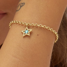 Carica l'immagine nel visualizzatore di Gallery, bracciale con pendente a forma di stella in Acciaio dorato con cristallo azzurro al centro, indossato e visto da vicino
